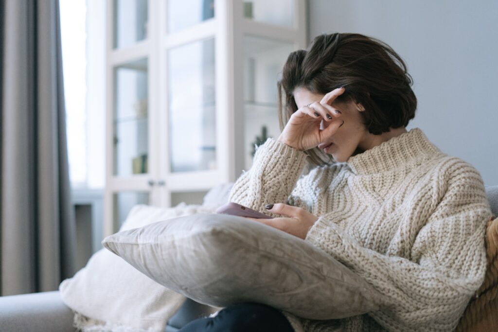 Woman looking at her phone in distress after discovering long-distance infidelity
