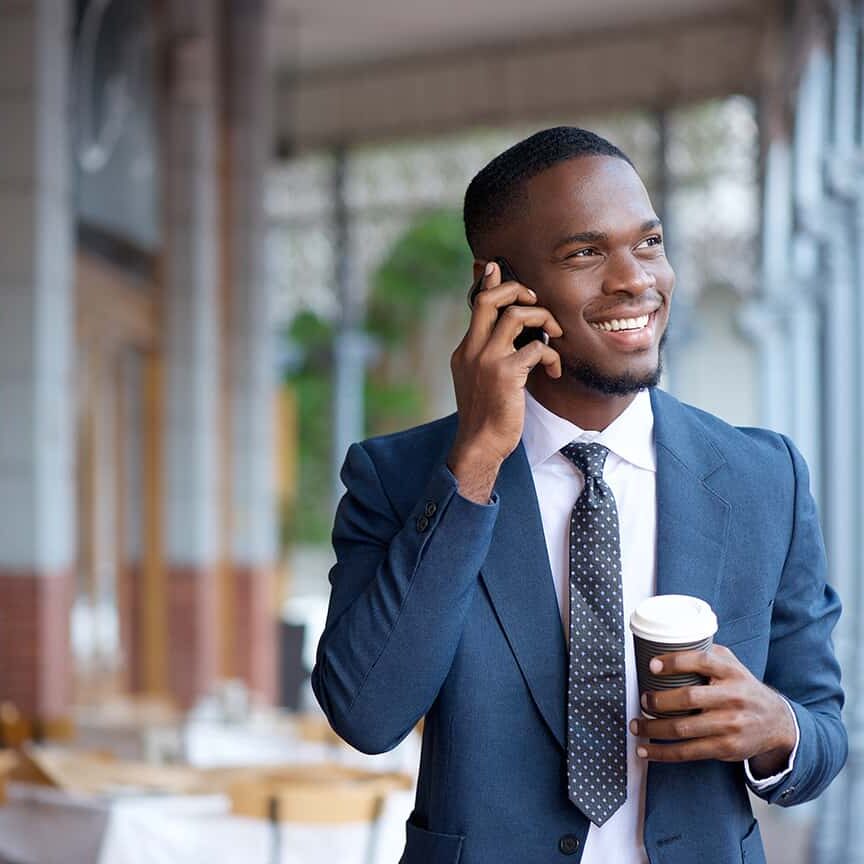 Portrait of a smiling businessman walking and talking on mobile phone